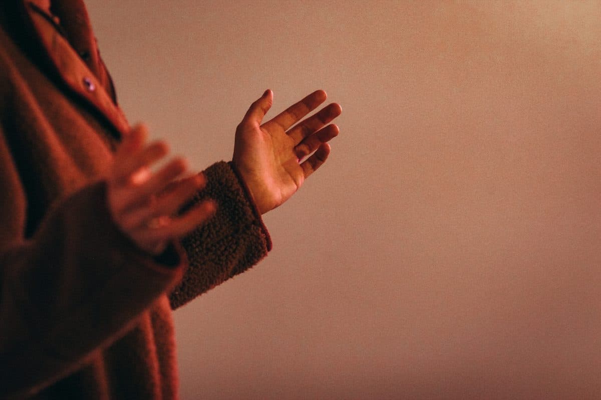 Warm, low-lit photo of hands raised in praise